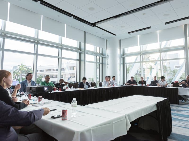 Industry leaders in session at a TIACA Executive Summit boardroom overlooking Miami