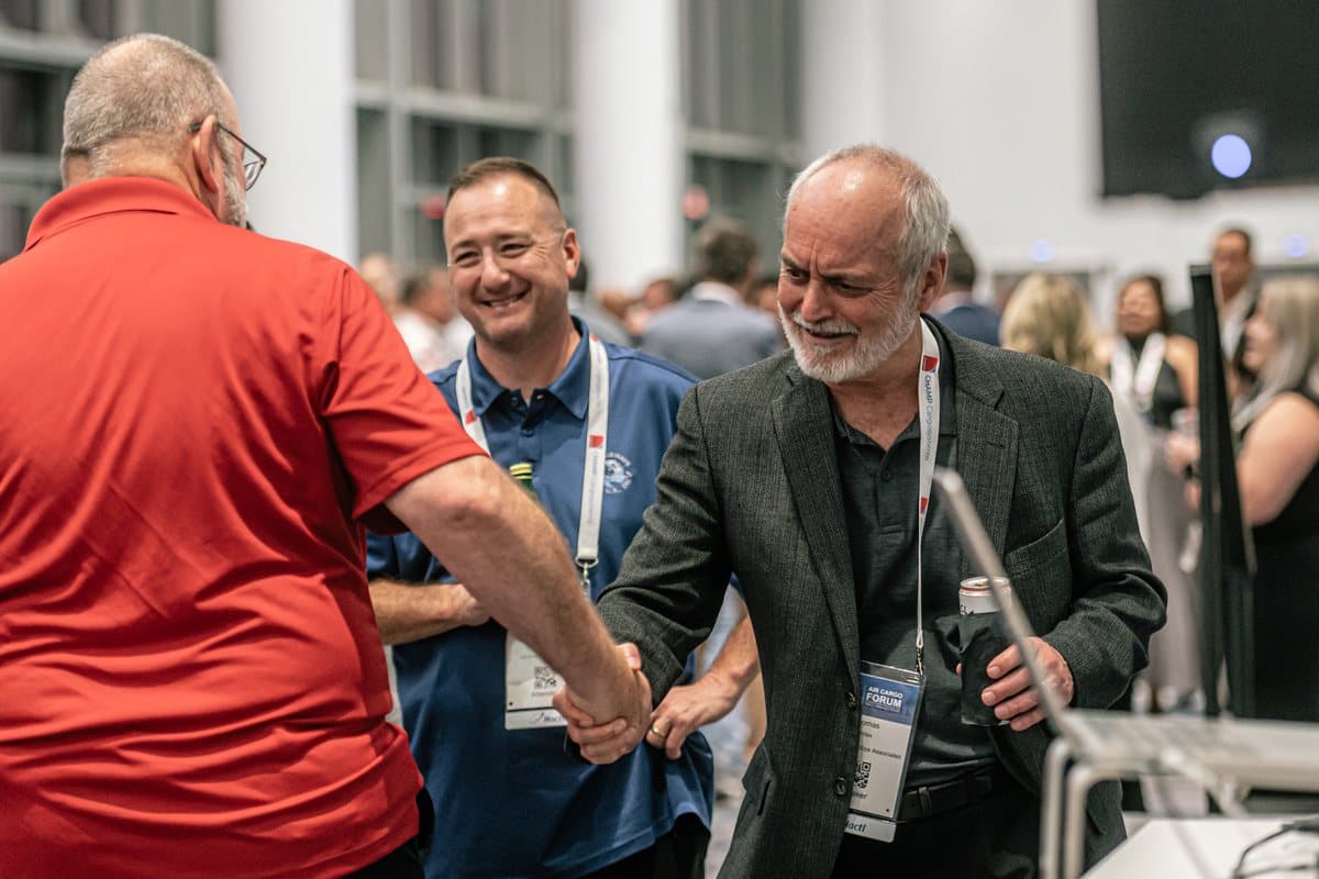 Two delegates shaking hands and laughing at the Air Cargo Forum