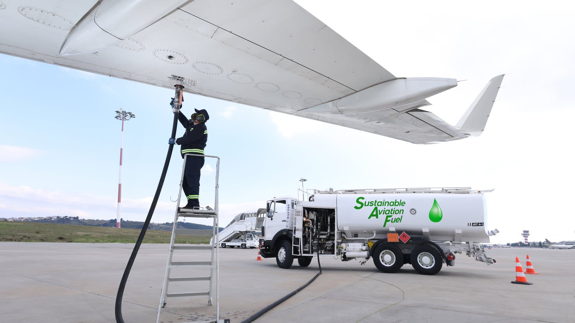 A technician refuelling an aircraft from a sustainable aviation fuel tanker